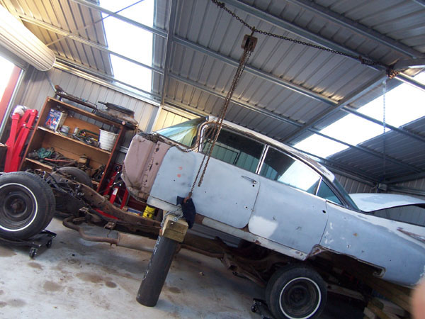 Cadillac is held in air by come along as it is raised off frame.
